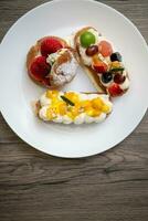 köstlich Choux Gebäck mit Vanillepudding, sortiert Früchte und Glasur Pulver auf hölzern Hintergrund. foto