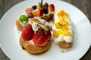 köstlich Choux Gebäck mit Vanillepudding, sortiert Früchte und Glasur Pulver auf hölzern Hintergrund. foto