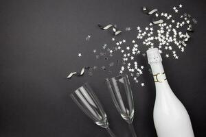 Champagner Flasche, Wein Brille und Konfetti auf dunkel Hintergrund. eben legen Komposition von Feier. oben Sicht. Kopieren Raum. foto