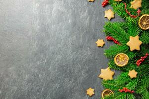 Weihnachten traditionell Lebkuchen Sterne mit Dekoration, Gewürze und Weihnachten Baum Geäst auf ein dunkel Stein Hintergrund. oben Sicht. Kopieren Raum. foto