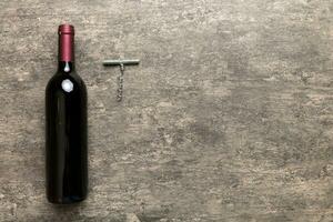 einer Flasche von rot Wein mit Korkenzieher auf farbig Tisch. eben legen, oben Aussicht mit Kopieren Raum foto