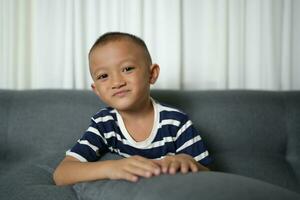 glücklich lächelnd asiatisch Junge auf das Sofa Innerhalb das Haus. foto