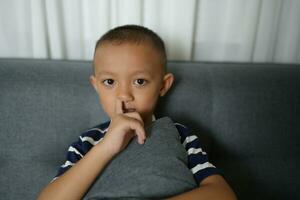 asiatisch Junge stößt seine Nase mit seine Finger foto