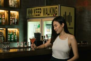 asiatische Frau, die nachts einen Cocktail in einer Bar trinkt. foto