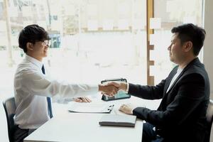 manager- und mitarbeiterinterviewkonzept mit händedruck nach gespräch über vertragsunterzeichnung. foto