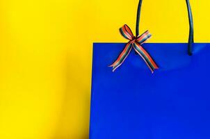 Blau Einkaufen Papier Tasche mit Band auf Gelb Hintergrund zum schwarz Freitag Einkaufen Verkauf Konzept. foto
