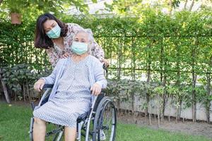 Helfen Sie asiatischen Senioren, die im Rollstuhl sitzen und eine Maske tragen, um das Coronavirus zu schützen. foto