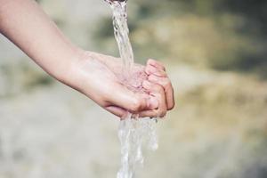 Hand fängt Wassertropfen auf, die aus dem Wasserhahn kommen foto