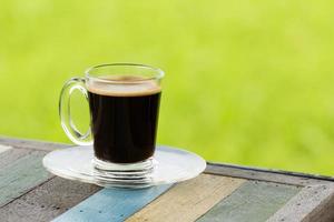 heißer schwarzer Kaffee auf Holztisch mit grünem Naturhintergrund foto