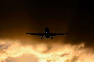 ein Flugzeug fliegend durch das Wolken beim Sonnenuntergang foto