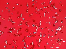 Konfettifolienstücke auf rotem Grund. abstrakte festliche Kulisse. foto