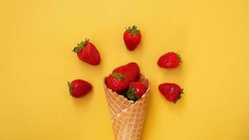 Eistüte mit Erdbeeren auf gelbem Grund