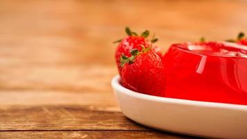 rotes Erdbeergelee mit Beeren auf einem weißen Teller foto