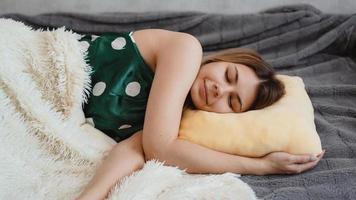 schönes junges Mädchen in einem grünen Nachthemd schläft auf einem gelben Kissen