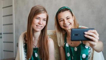 schöne glückliche Freundinnen, die Selfie mit Smartphone machen foto