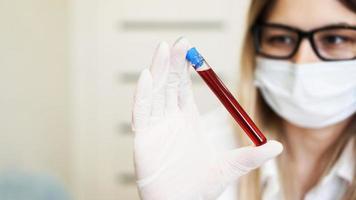 Nahaufnahme einer jungen Wissenschaftlerin, die ein Reagenzglas mit Blutprobe hält? foto