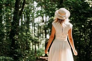 schöne junge Frau mit Strohhut und weißem Kleid in einem grünen Park foto