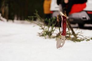 Touristenmesser und Lagerfeuer im Winterwald. foto