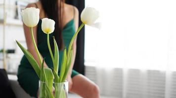 weiße Tulpen in einer Vase. verschwommener Hintergrund - Frau in einem grünen Kleid