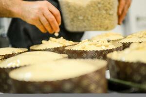 Koch produzieren Panettone, während lievitieren, Hinzufügen Mandel Zucker Belag zu roh Süss Brot. foto