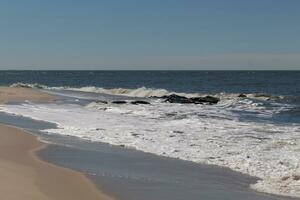 diese ist Sonnenuntergang Strand beim Kap kann Neu Jersey. das schön Sand liegt alle um mit anders Schatten von braun zeigen wo das Wellen berührt. das weiße Kappen von das Surfen zeigen das Gezeiten von das Meer. foto