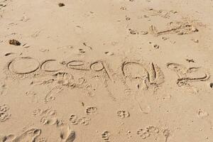 schön braun Sand mit Schreiben geätzt In. das Wort Ozean können Sein gesehen geschrieben Ion das Strand. Fußabdrücke können Sein gesehen alle um. foto