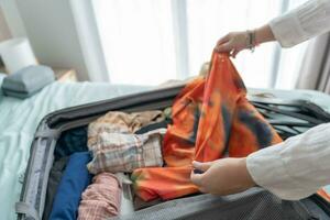 Frau Verpackung Koffer auf Bett zum ein Neu Reise Verpackung aufführen zum Reise Planung vorbereiten Ferien Buch jetzt Reisen Transport foto