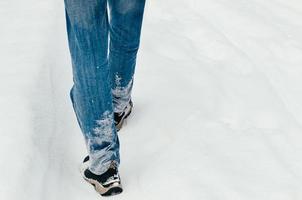 Rückansicht der männlichen Beine, die im Schnee laufen foto