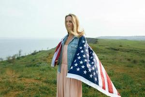 ein mädchen in einem korallenkleid und einer jeansjacke hält die flagge von usa foto