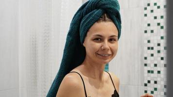 glückliche Frau im Badezimmer mit Handtuch auf dem Kopf