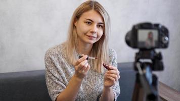Vloggerin, die Lippenstift zeigt. Beauty-Bloggerin im Homestudio foto