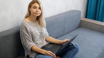 lässige junge Frau mit Laptop im Wohnzimmer