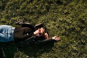 schöne gesunde junge frau, die auf dem grünen gras liegt und sich entspannt foto