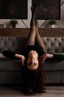 schöne junge Frau in einer schwarzen transparenten Strumpfhose auf einer Couch foto
