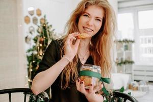 glückliche junge Frau, die Weihnachtsplätzchen in der Küche isst