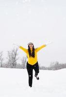 junge brünette Frau, die mit Schnee im Park spielt foto