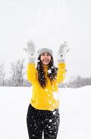 junge brünette Frau, die mit Schnee im Park spielt foto