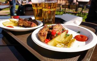 Schweinerippchen auf einem Tablett und helles Bier. Straßenessen. Festivalessen foto