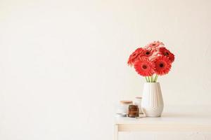 helle Gerbera-Gänseblümchen in weißer Vase auf Küchentisch, minimalistischer Stil foto