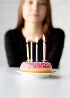 Teenager-Geburtstagsmädchen bläst Kerzen auf dem Donut foto