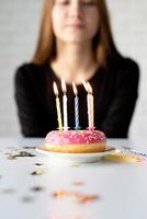 Teenager-Geburtstagsmädchen bläst Kerzen auf dem Donut foto
