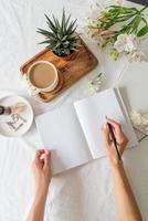 Geöffnetes Buch, Kaffee und Blumen Draufsicht auf weißes Bett. Mock-up-Design foto