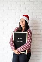 Frau in Weihnachtsmütze mit schwarzer Buchstabentafel foto