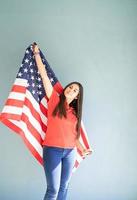 schöne junge Frau mit amerikanischer Flagge auf blauem Hintergrund foto