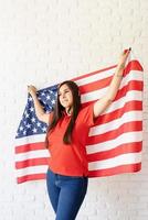 schöne junge Frau mit amerikanischer Flagge, ausgestreckten Armen foto