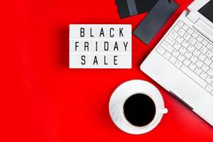 Black Friday-Verkaufskonzept. Laptop und Kaffeetasse auf rotem Grund. foto