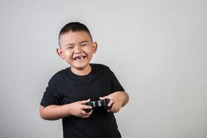 glücklicher Junge spielt Spielcomputer mit einem Controller im Studiofoto foto