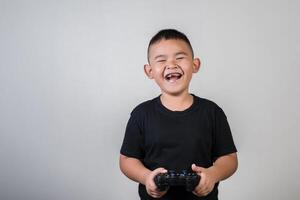 glücklicher Junge spielt Spielcomputer mit einem Controller im Studiofoto foto