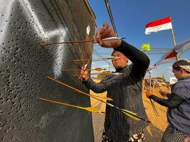 Klaten, Indonesien, August 15, 2023. männlich und weiblich Teilnehmer, gekleidet im javanisch Benutzerdefiniert gezogen seine Bogen durch Schielen zu leisten Konzentration von Ziel Richtigkeit im traditionell javanisch Pfeil trad. foto