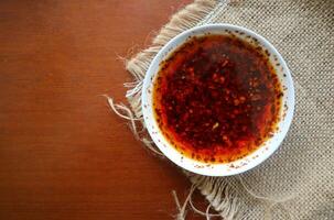 Chili Öl. hausgemacht Chili Öl im ein Glas liite Platte, auf Tabelle foto